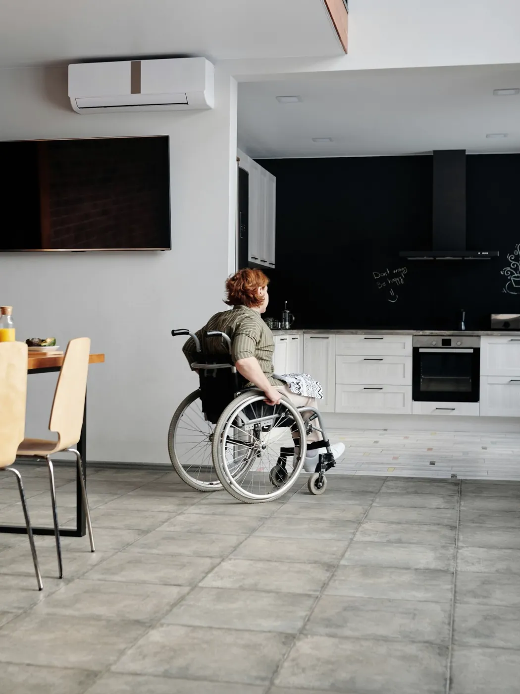 A woman in a wheelchair moves through a step-free, open-plan kitchen and dining space.